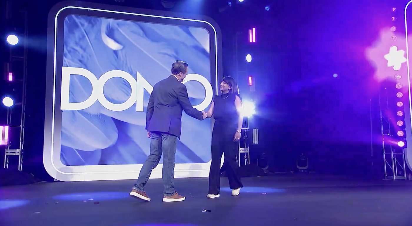 Jani shaking hands on stage in front of the DOMO logo