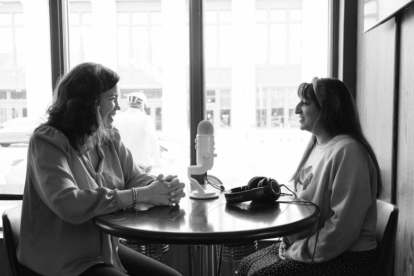 Jani Rad recording a podcast episode across a cafe table